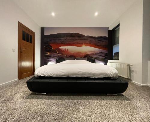 um quarto com uma cama com um quadro na parede em Modern 1BR house near Heysel, Expo, Palais 12, Atomium, UZVUB et stade Roi Baudouin em Wemmel