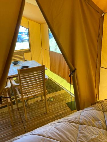 Zimmer mit einem Tisch und einem Stuhl in einem Zelt in der Unterkunft Oh! Campings - Camping Paradis A l'ombre des tilleuls in Peyrouse