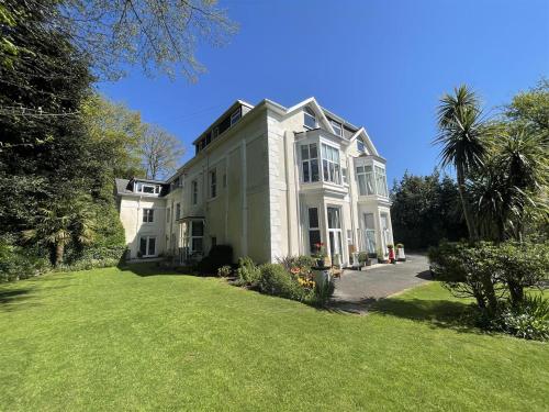a large white house with a large yard at Cozy seaside hideaway with free parking in Torquay