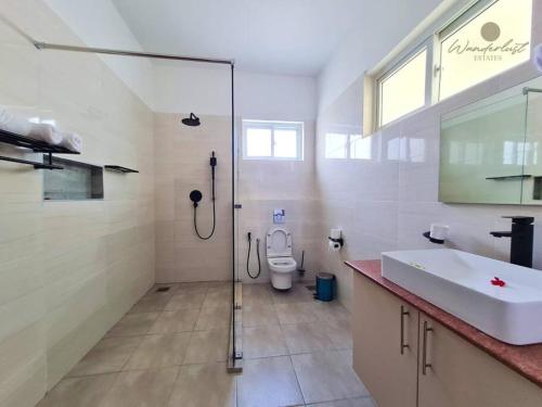 uma casa de banho com um chuveiro, um lavatório e um WC. em Fiorella Beach House, Diani Beach em Praia de Diani