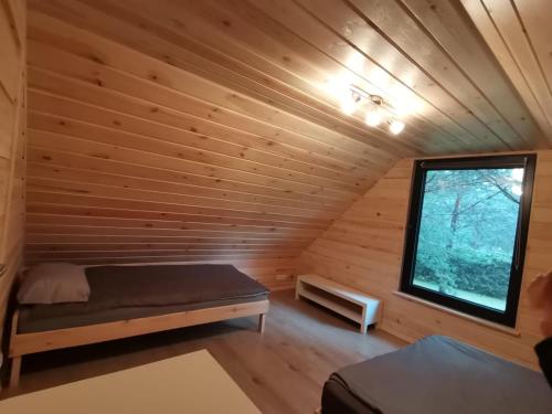 a bedroom in a log cabin with a bed and a window at Między Sosnami in Pasym