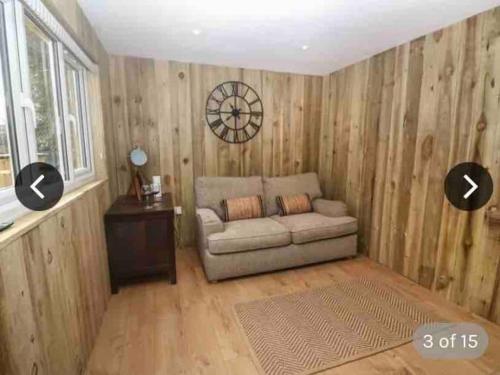 a living room with a couch and a clock on the wall at Hunting Gate Lodge in Redruth