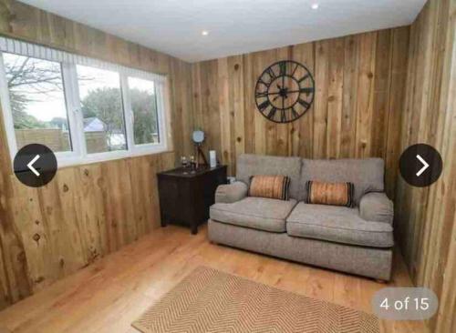 a living room with a couch and a clock on the wall at Hunting Gate Lodge in Redruth