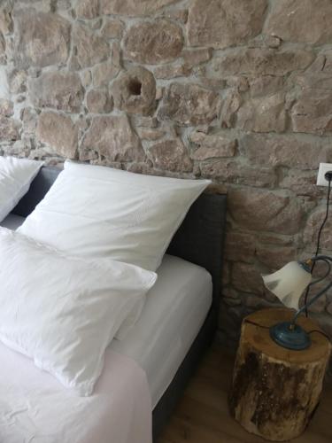 uma cama com almofadas brancas e uma parede de pedra em Ferienwohnung Höfenhof em Schiltach