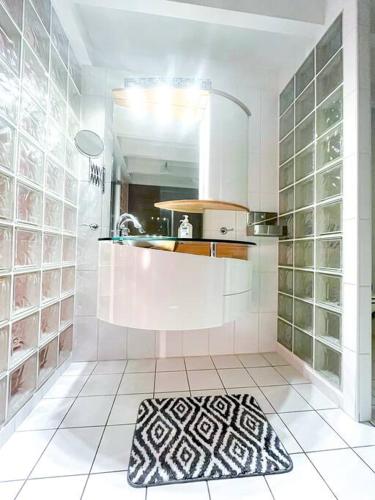 - une cuisine blanche avec un évier et un miroir dans l'établissement Le Rousseau • Haut standing • Duplex • Centre-ville, à Châteauroux