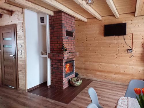 a living room with a brick fireplace and a tv at Domek Na Starej Cegielni in Baligród