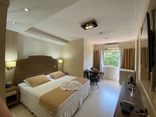 um quarto com uma cama, uma secretária e uma janela em Kanoa Hotel em Santo Antônio da Platina