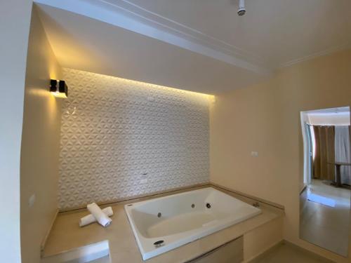 a white bath tub in a bathroom with a light at Kanoa Hotel in Santo Antônio da Platina