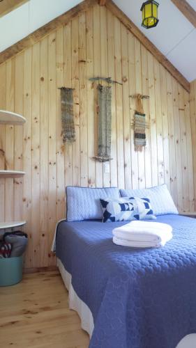 - une chambre avec un lit bleu et un mur en bois dans l'établissement Cabañas Sotobosque, à Puelo