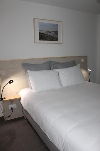 - une chambre avec un lit blanc et une table de nuit dans l'établissement Appt avec balcon St Valery / Somme parking privatif 3/4 pers, à Saint-Valery-sur-Somme