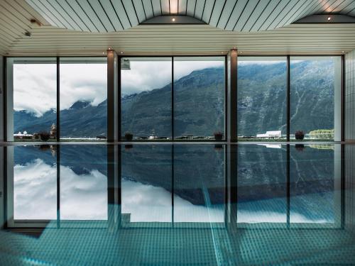 a room with a swimming pool with a view of a mountain at Hotel Ullensvang in Lofthus