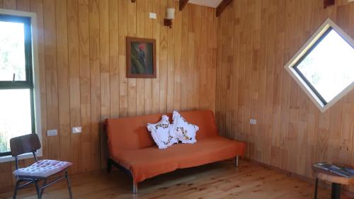 une chaise orange dans une chambre avec fenêtre dans l'établissement Cabañas Sotobosque, à Puelo