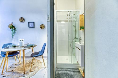 y baño con mesa, sillas y ducha. en R'Apparts Studio Le Petit Paradis, en Grenoble