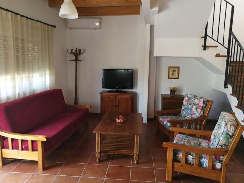 sala de estar con sofá, sillas y TV en Casa La Higuera en Chulilla
