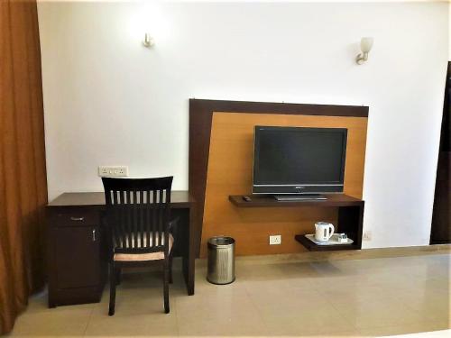 Cette chambre comprend un bureau avec une télévision et une chaise. dans l'établissement Tavisha Villa Flim City Road Dadri Road, à Noida