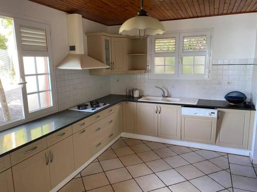 uma cozinha com armários brancos e bancadas pretas em Magnifique Villa Collinos avec piscine et jardin em Schœlcher