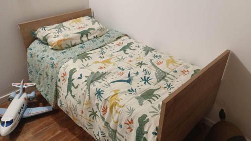 Una cama en un dormitorio con una colcha con dinosaurios. en My home by corte, en Cazilhac