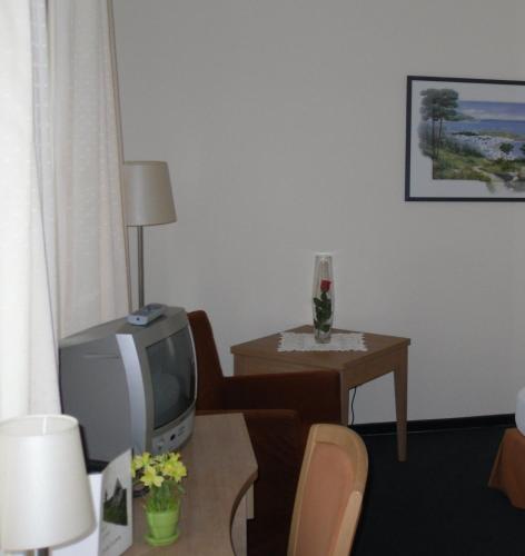 ein Wohnzimmer mit einem TV und einem Tisch mit einem Tisch in der Unterkunft Gästehaus Zum Lamm in Lauda-Königshofen
