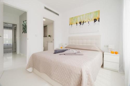 a white bedroom with a bed and a painting on the wall at Modern villa with pool jacuzzi and sea view in La Horadada