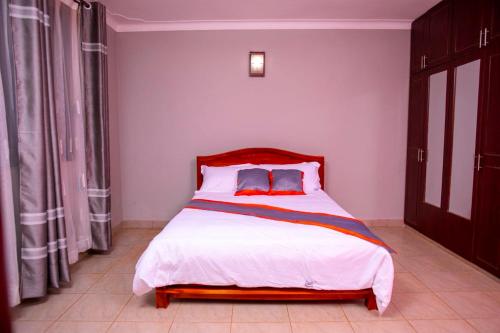 a bedroom with a large bed with a red headboard at Karay Apartments in Wakiso