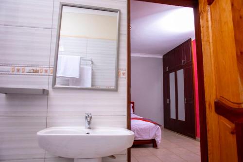 a bathroom with a sink and a mirror at Karay Apartments in Wakiso