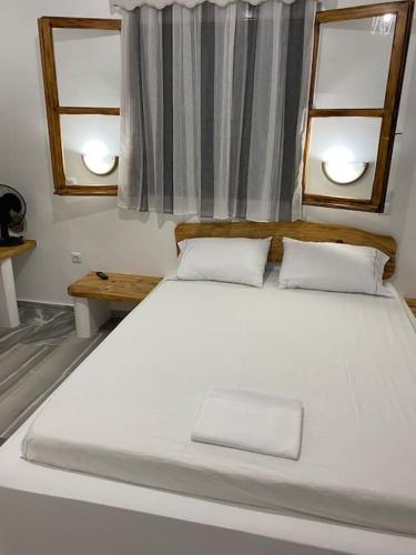 a large white bed in a room with two windows at George's Home Platy Gyalos in Kalymnos