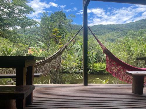 a hammock on a deck with a view of a river at Pousada Meraki Paraty Mirim in Paraty