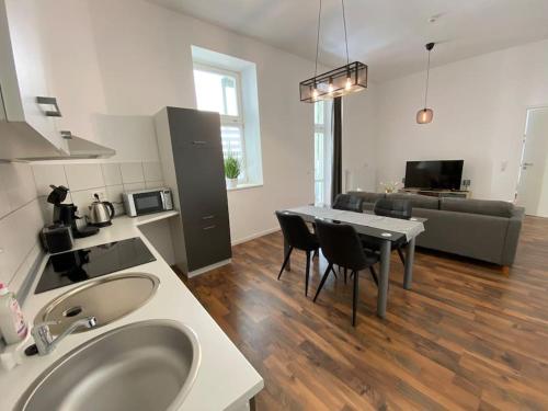 Il comprend une cuisine et un salon avec une table et des chaises. dans l'établissement AKK3 Apartment Magdeburg Altstadt Zentral Balkon, à Magdebourg