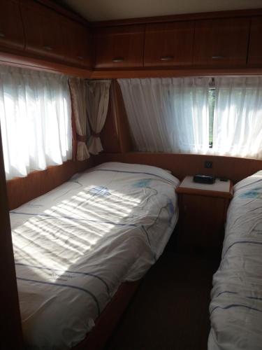 Habitación pequeña con 1 cama y 2 ventanas en Forrás camping, en Magyarhertelend