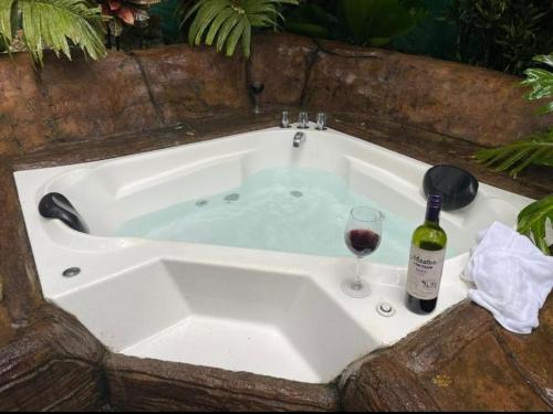 a bath tub with a bottle of wine and a glass at Momotus Glamping in Florencia