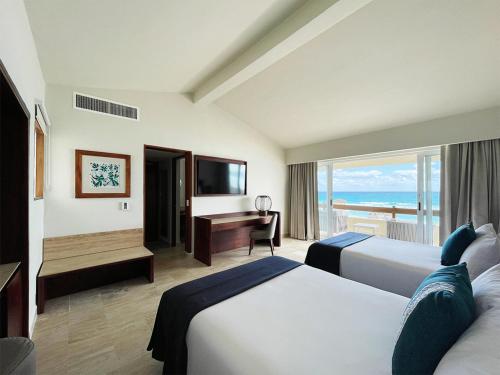 Habitación de hotel con 2 camas, escritorio y ventana en The Villas Cancun by Grand Park Royal - All Inclusive en Cancún