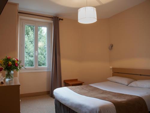 a bedroom with a large bed and a window at Hôtel des Pyrénées in Angoulême