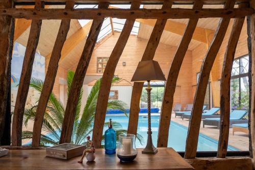 a table with a lamp on a table in a room with a pool at Nature et Lin in Néville