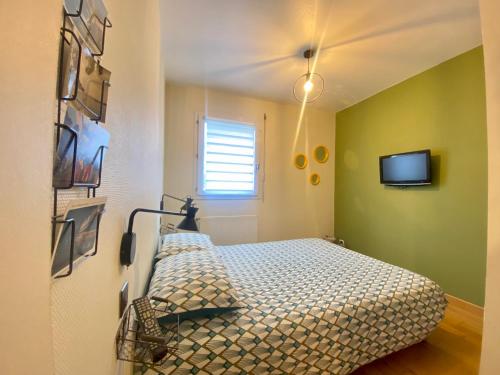 ein Schlafzimmer mit einem Bett und einem TV an der Wand in der Unterkunft La Pause de Mérimée - T2 - Parking - Jardin in Vannes