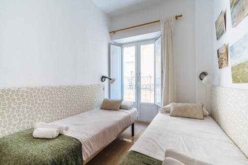 two beds in a room with a window at Preciosa Casa Independiente Alfalfa, Parking Optional in Seville