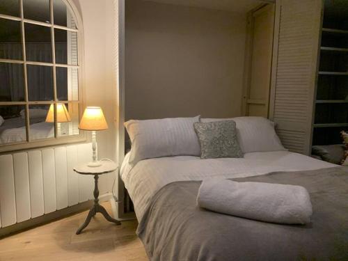a bedroom with a bed and a table with a lamp at Log Studio near Le Manoir aux Quat’Saisons, Oxford in Great Milton