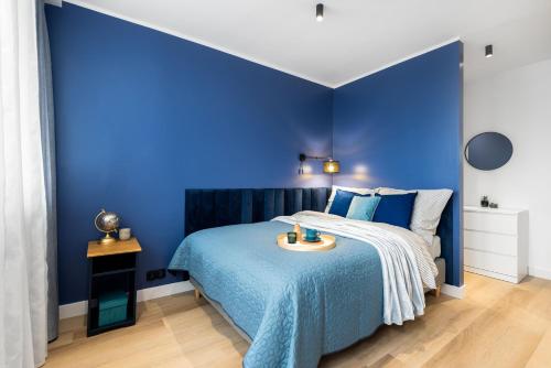 ein blaues Schlafzimmer mit einem Bett mit blauer Wand in der Unterkunft Apartament Gold - darmowy Parking, ścisłe centrum - by Kairos Apartments in Gliwice