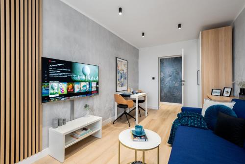 a living room with a blue couch and a tv at Kairos Apartments - Gold - darmowy Parking, ścisłe centrum in Gliwice