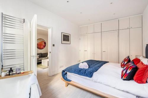 a bedroom with a bed with red and blue pillows at Chelsea Posh apartment in London