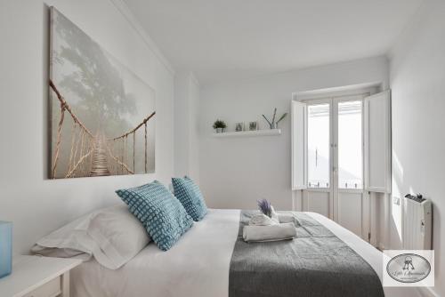 Un dormitorio blanco con una cama grande con almohadas azules. en Dulce Arbolí Little Apartments, en Cádiz