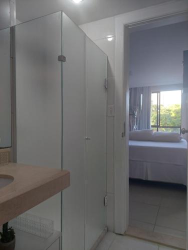a white bathroom with a shower and a bedroom at Apart-Flat Atlantic City Salvador in Salvador
