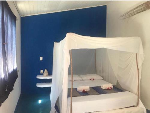 a white bed with a canopy in a room at Casa Colorida in Pipa