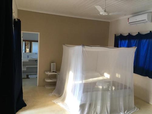 a room with a bed with a white curtain at Casa Colorida in Pipa