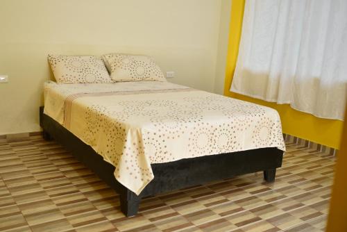 a bedroom with a bed with a yellow and white blanket at Hotel Tari in Mocoa