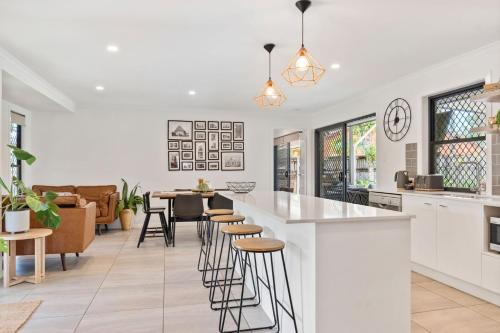 cocina y sala de estar con encimera y taburetes en 4 bedroom gem with air conditioning, a great outdoor area including pool and you can bring a small dog., en Maroochydore