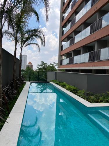 - une piscine en face d'un bâtiment avec des palmiers dans l'établissement São Paulo - Vila Mariana - Central, à São Paulo