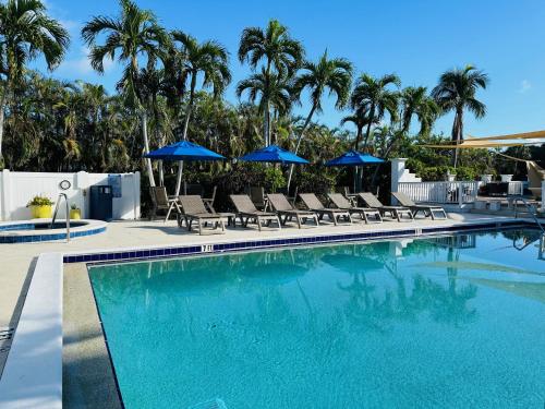 a swimming pool with chairs and blue umbrellas at Olde Marco Inn in Marco Island