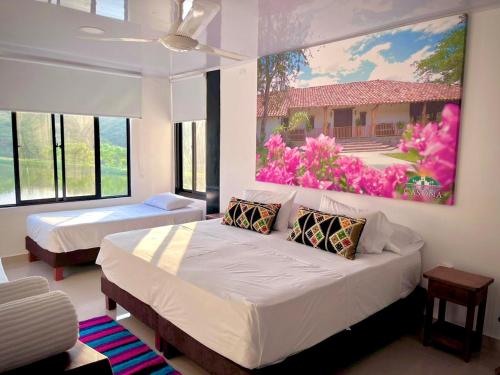 um quarto com duas camas e um quadro na parede em Hotel Parque la Casona em Garzón