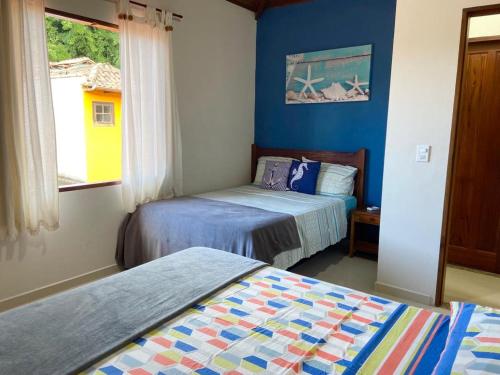 2 Betten in einem Zimmer mit blauen Wänden und einem Fenster in der Unterkunft Casa Aconchegante Paraty in Paraty
