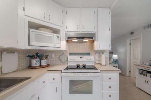 a kitchen with white cabinets and a stove top oven at Updated St. Pete Beachside Condo in St. Pete Beach